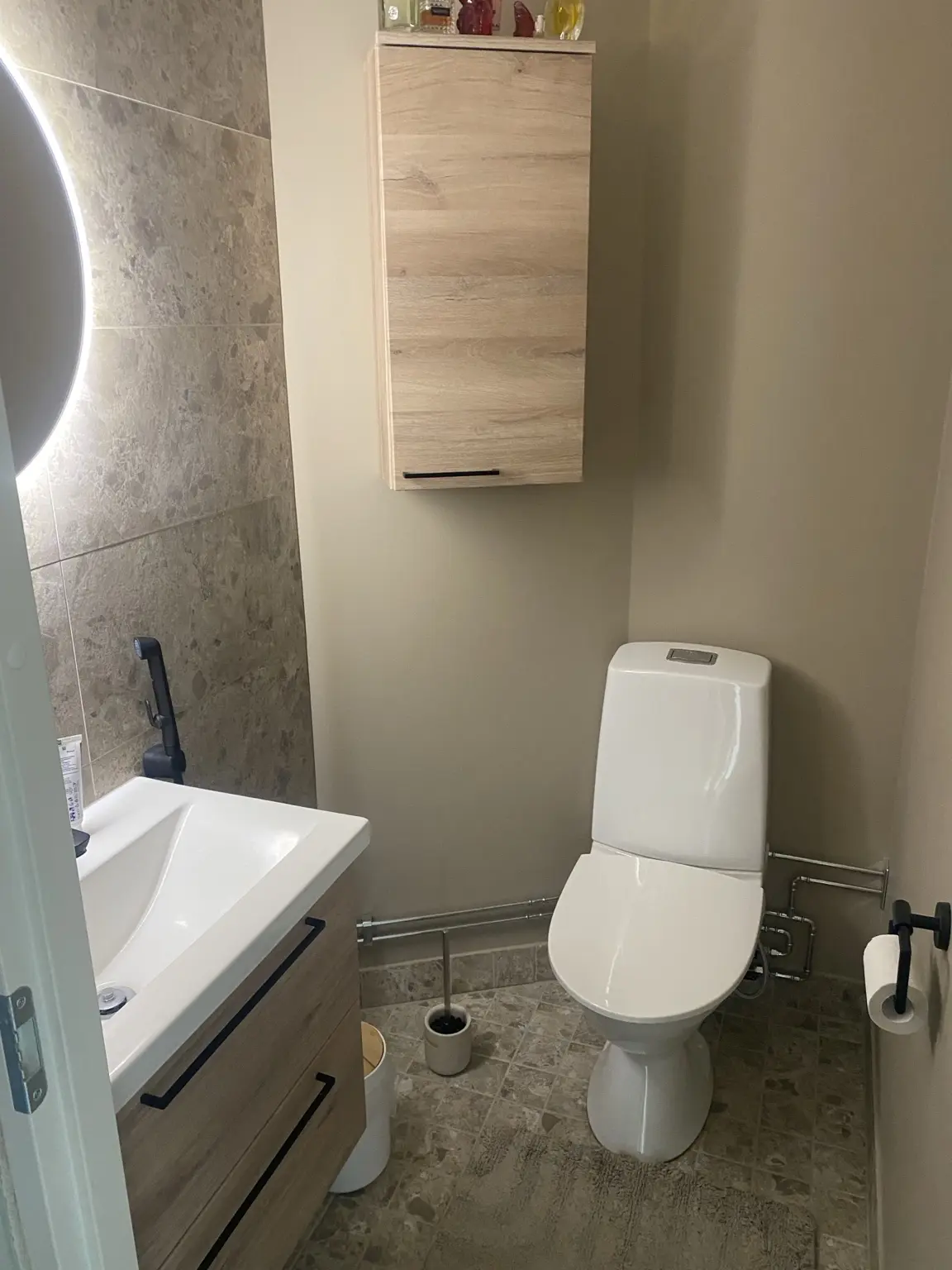 WC-tila, valkoiset kalusteet ja kivipintainen lattia